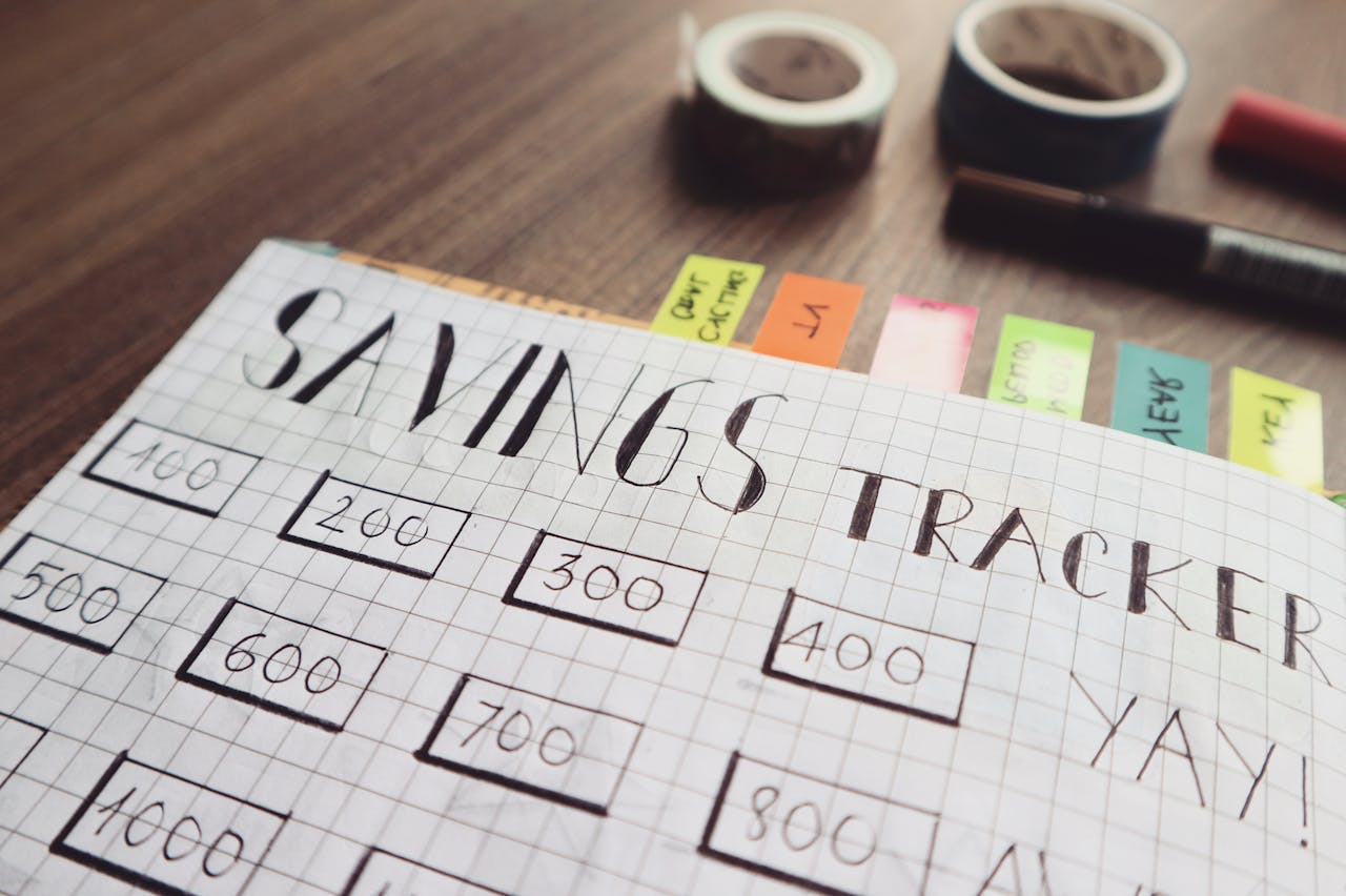 who-we-are Close-up of a handmade savings tracker with colored tabs on a wooden table, ideal for financial planning visuals.